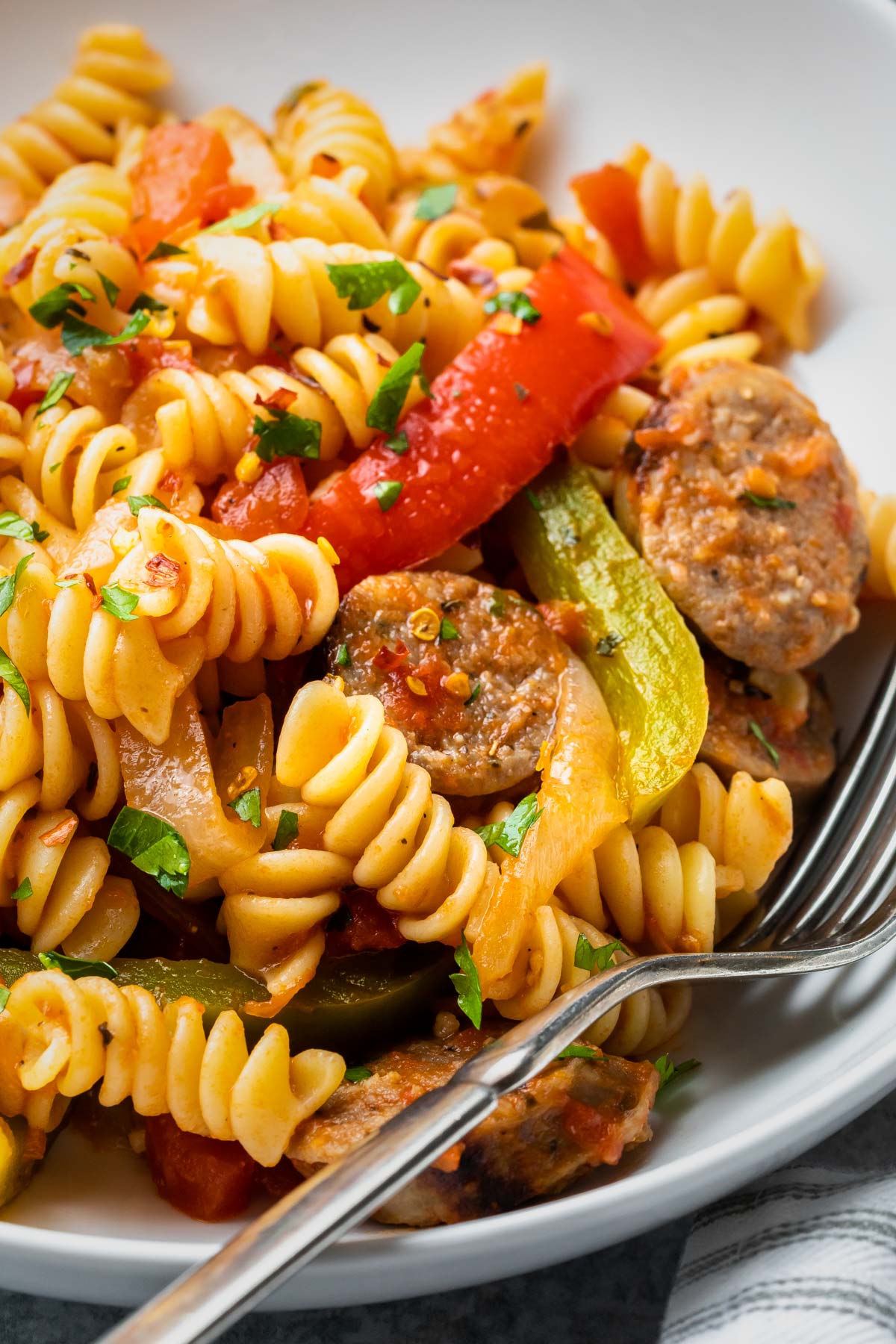 close up of rotini pasta with green and red bell peppers and italian sausage slices