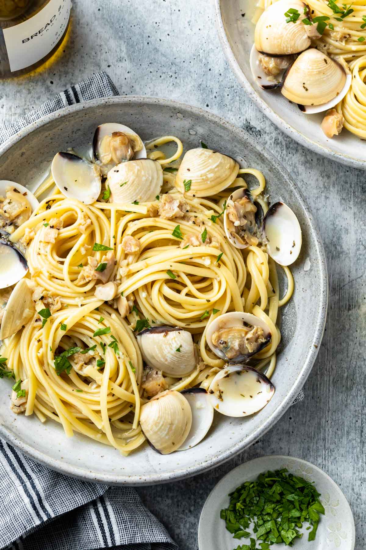Clams, in the shell and chopped, and linguine in a bowl, garnished with chopped parsley