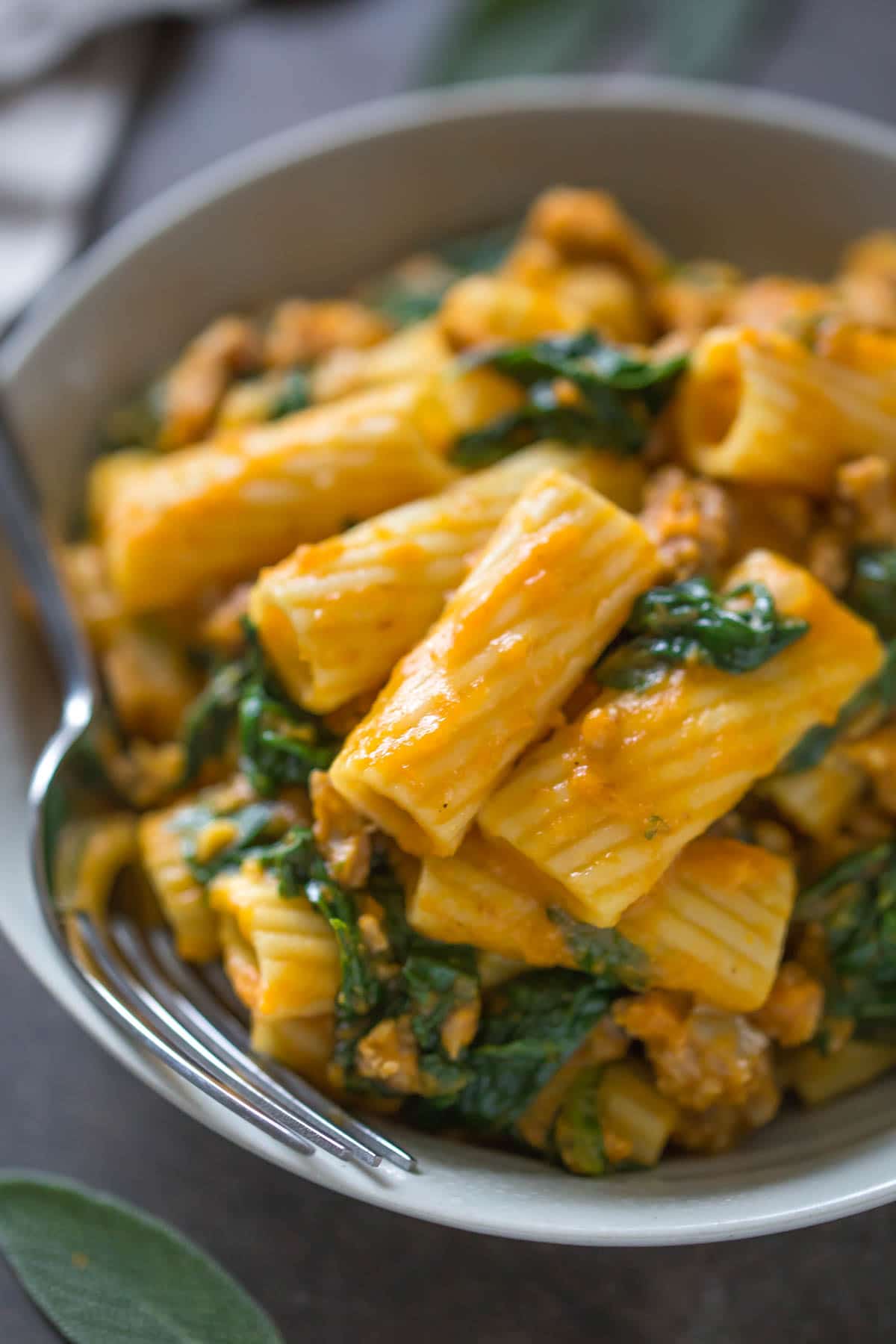 Close up of a bowl of rigatoni with sausage and spinach.