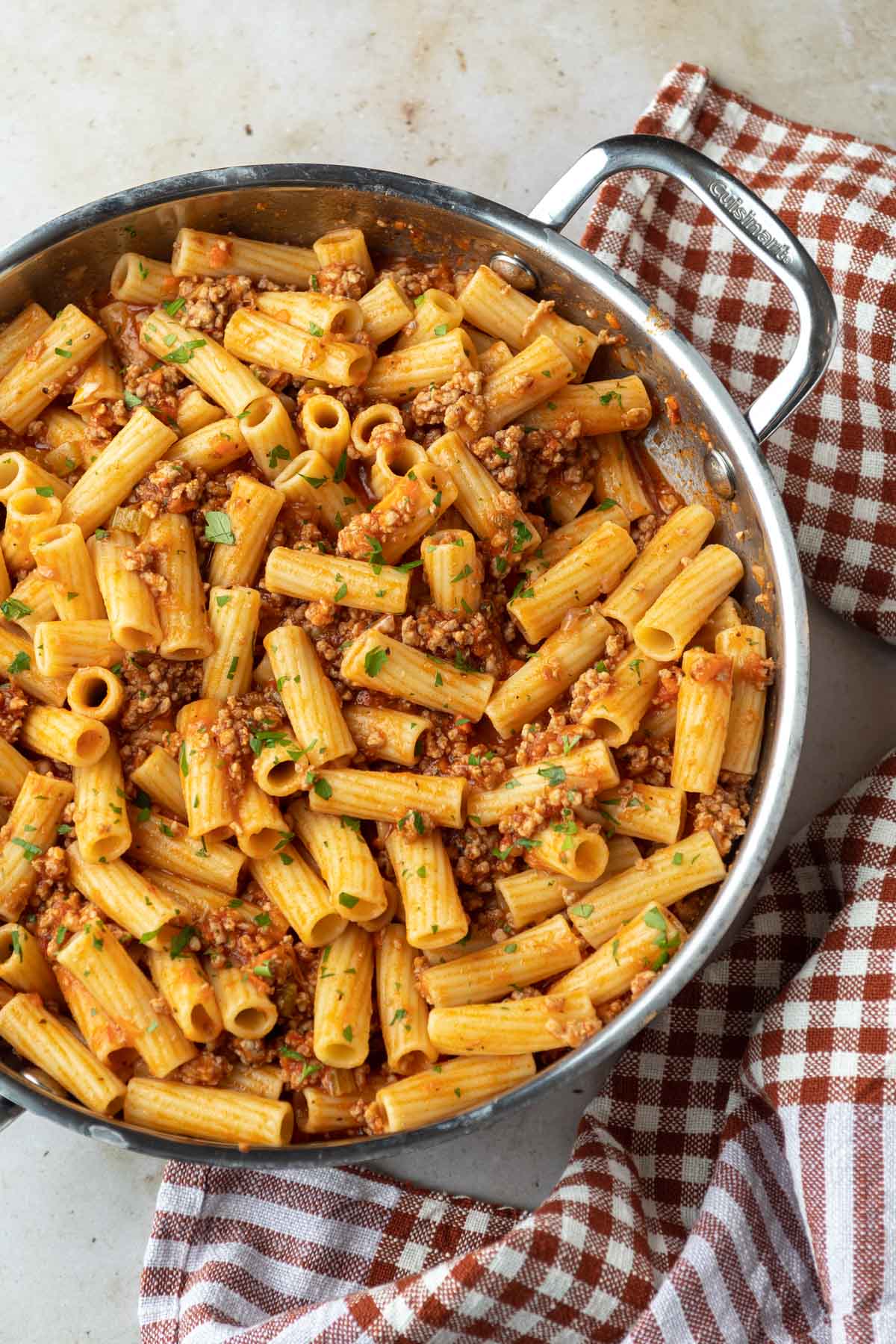 An overhead shot of a skillet full of rigatoni with pork ragu, garnished with fresh chopped parsley. 