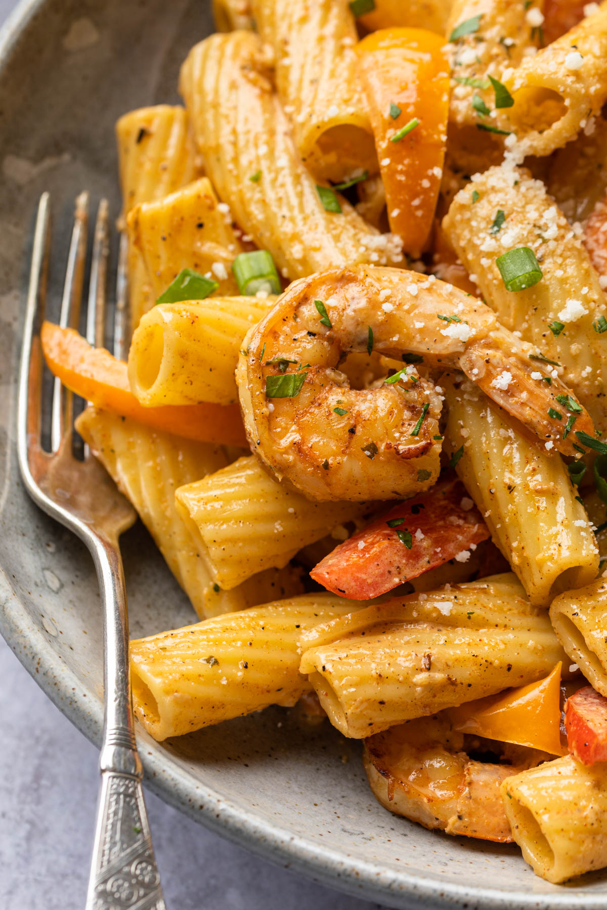 Close up of jerk shrimp pasta in a bowl, showing the shrimp, rigatoni and bell pepper slices. 
