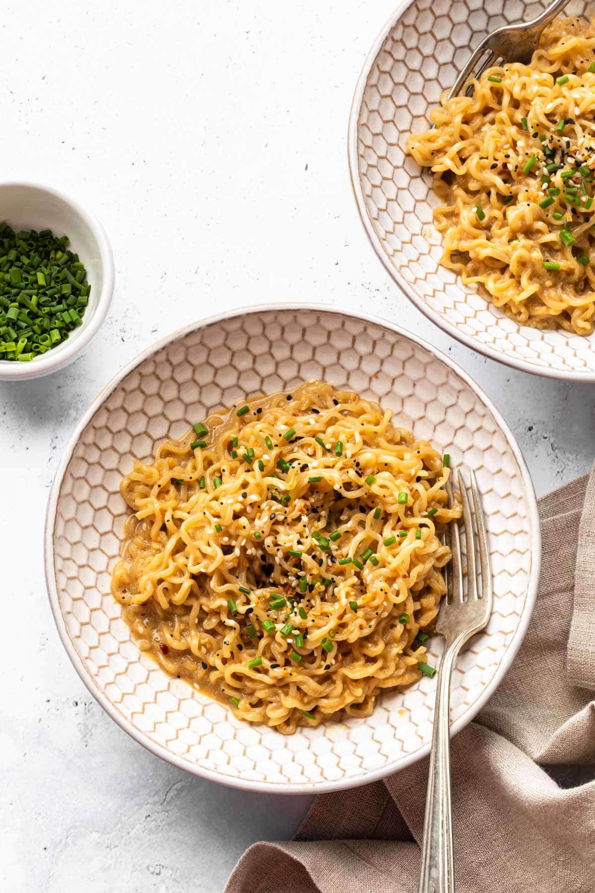 Ramen noodles in a bowl garnished with chives and sesame seeds. 