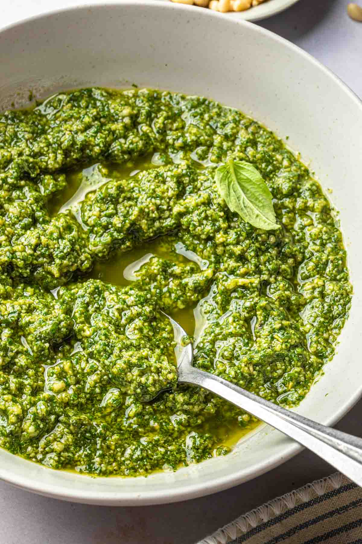A bowl of pesto sauce with a spoon in it. 