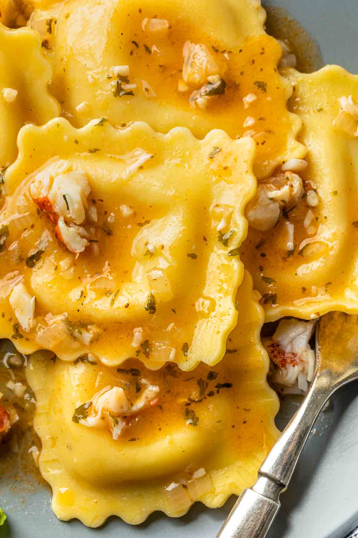 Close up of ravioli coated in a white wine lobster sauce. 