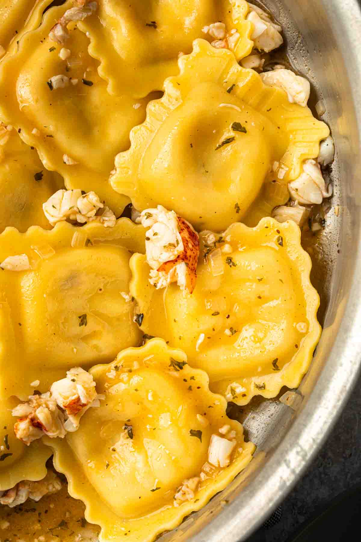 Lobster ravioli in a large skillet tossed in a butter sauce. 