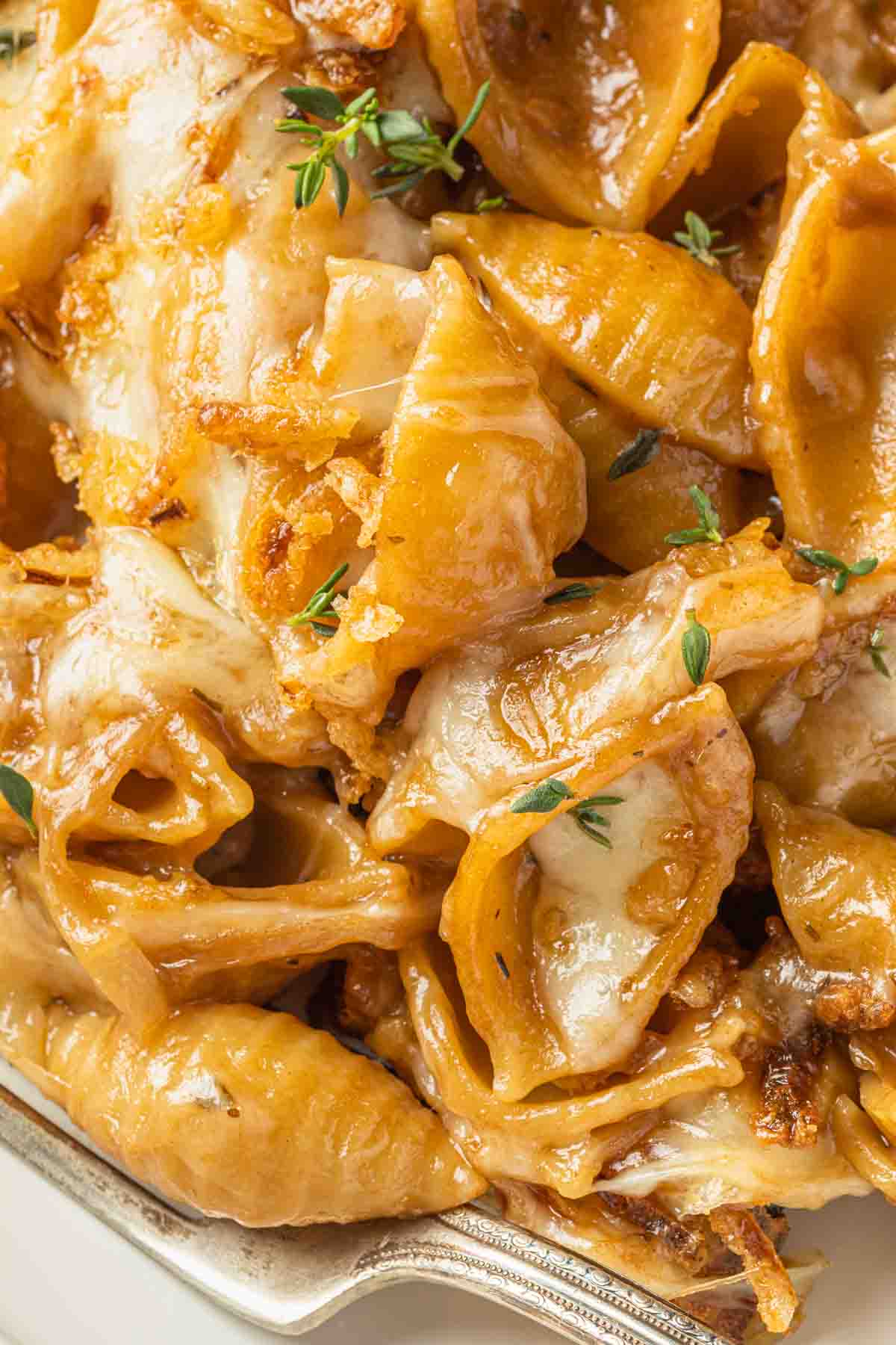 Close up of french onion pasta covered in gruyere cheese and crispy fried onions. 