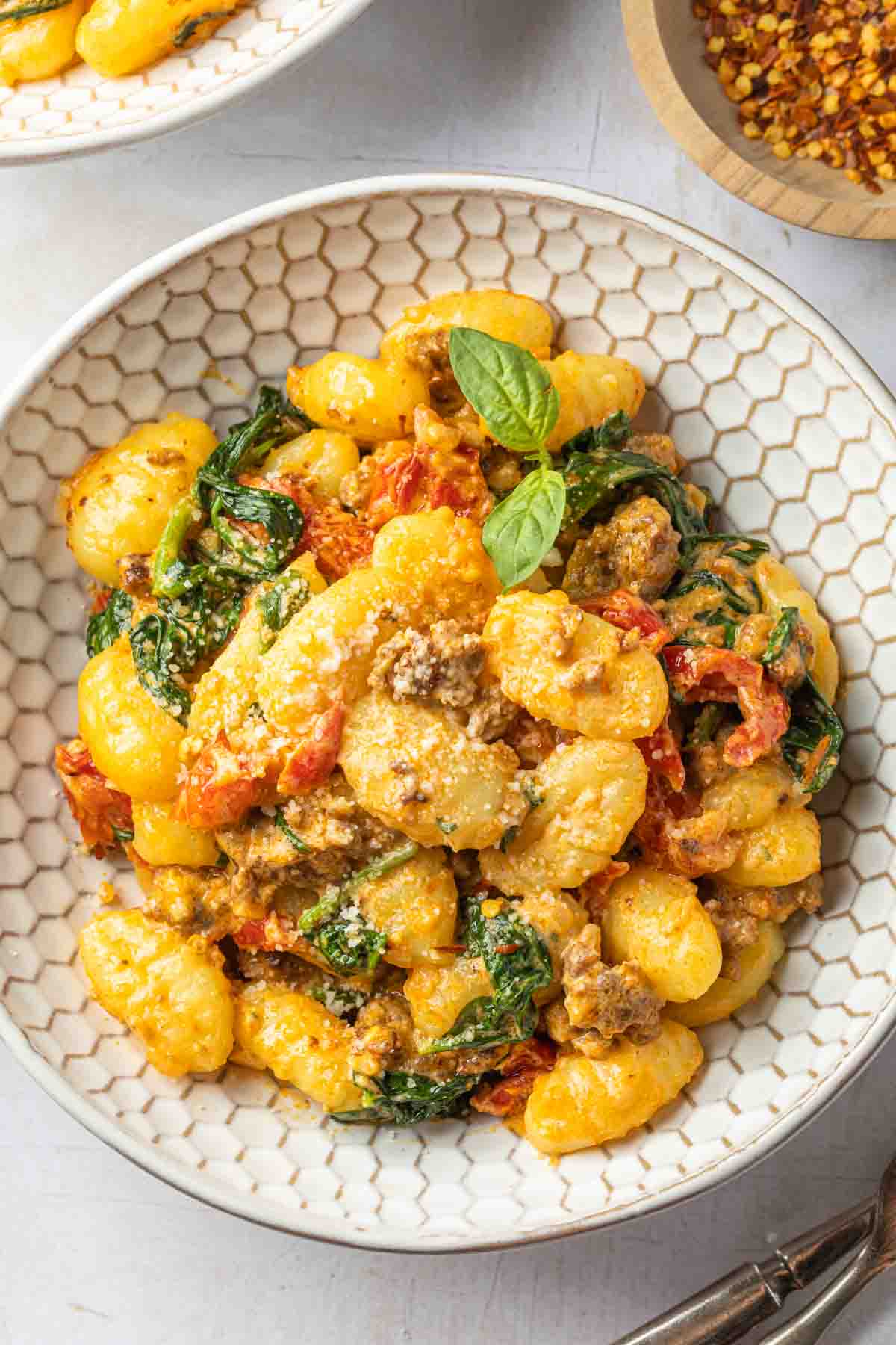 A bowl of gnocchi and chorizo sausage with spinach and sundried tomatoes in a creamy sauce.  
