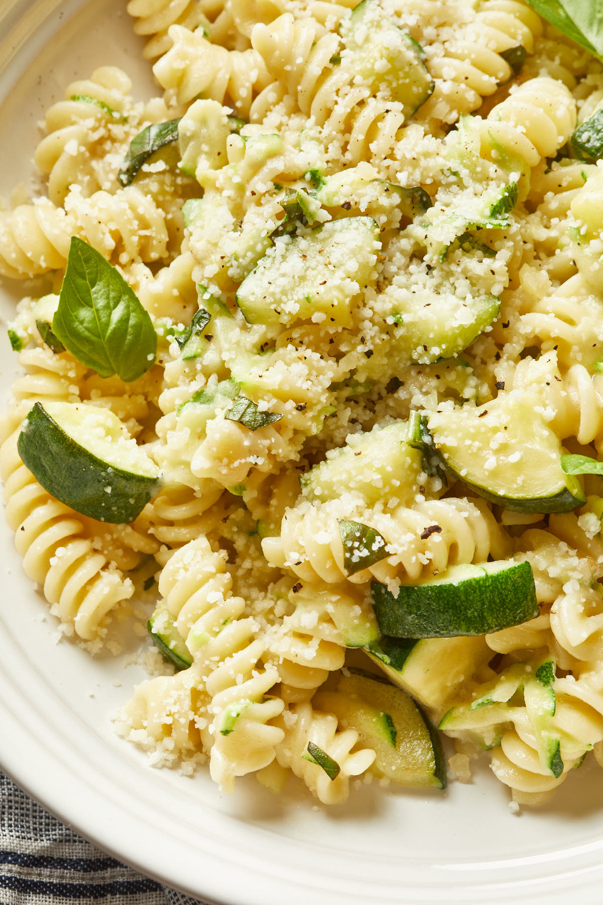 Close up of fusilli pasta made with a creamy sauce, with pieces of zucchini scattered throughout. 
